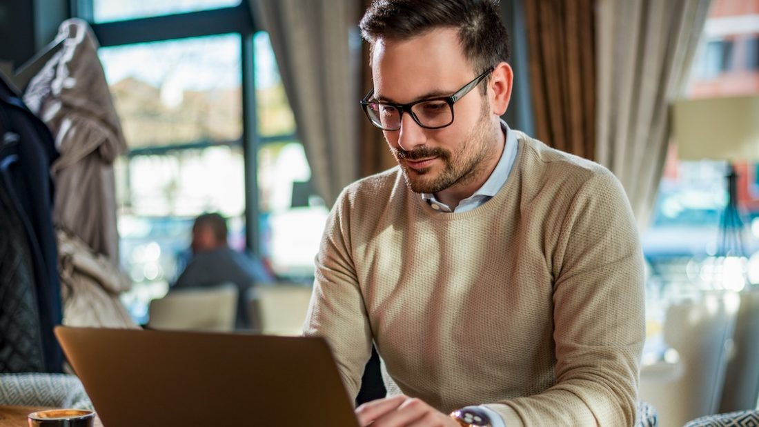 Mann sitzt zufrieden vor einem Laptop