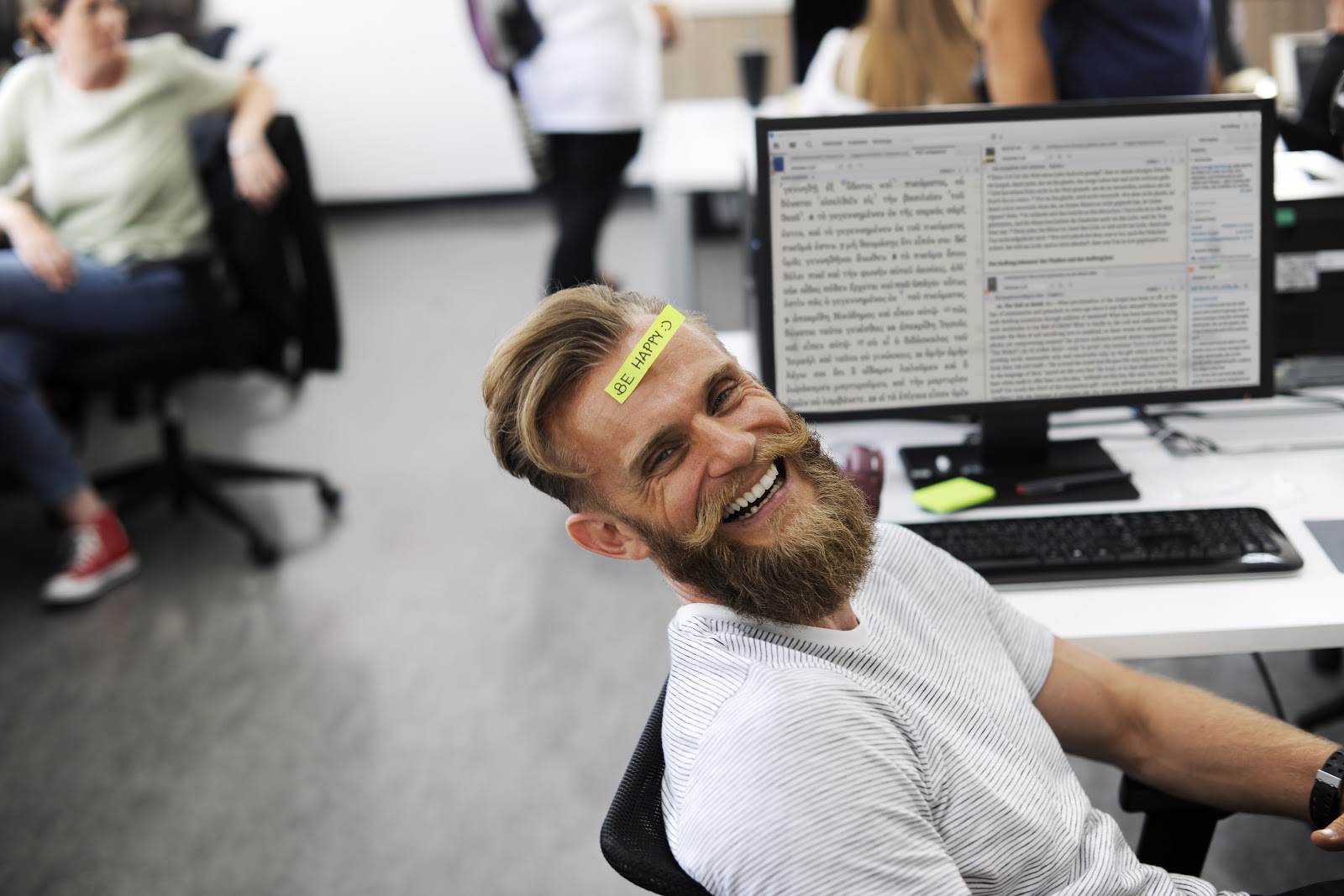 Bärtiger Mann im Bürostuhl mit Logos Bibelsoftware auf dem Bildschirm und den Worten BE HAPPY auf der Stirn